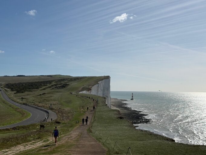 Runners on the edge of dramatic white chalk cliffs. The sea is to the right.