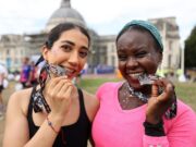 Cardiff parties for the 40th anniversary of Kidney Wales CDF 10K Two women smile while biting their running medals