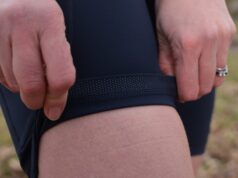 Close up navy shorts. Hands are turning up the leg seam to show a silicone grip on the inside
