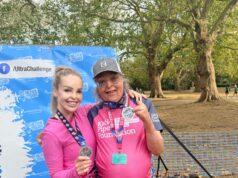A man and woman pose in pink tshirts with medals