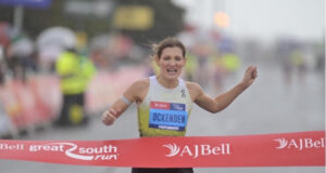 Woman runs hard through red tape of a finish line