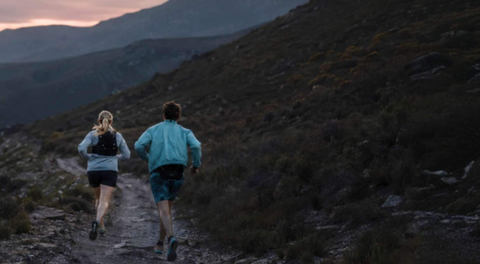 Forestry England/Runners Need A man an woman run along a hilly trail in low light