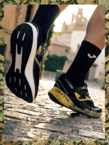 Close up a person's lower legs and feet running in black and yellow shoes