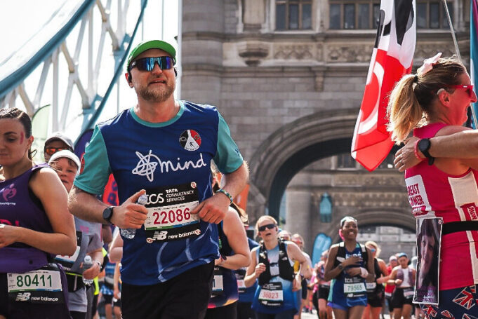 Tim Goule Man runs over Tower Bridge amongst lots of other runners.
