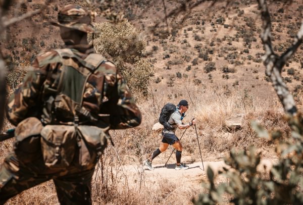 ForRangers Ultra Image shows back of a ranger in the froeground as an ultra runner passes in front of him in the distance.