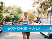 Oxford Half celebrates 15th birthday Woman runs through light blue finish tape saying Oxford Half