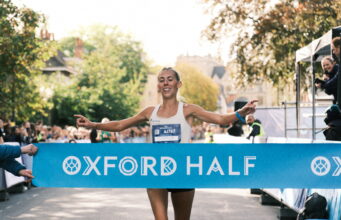 Oxford Half celebrates 15th birthday Woman runs through light blue finish tape saying Oxford Half