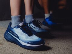 Two people wearing different coloured blue trainers - feet and lower part of legs are visible and it is dark