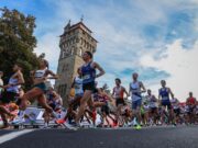 Ballot open for 2027 Cardiff Half Marathon A crowd of road runners running fast past a tower