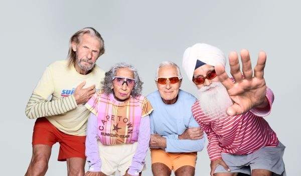 Britain’s oldest running team. Combined age: 321 4 runners in bright clothes, with grey hair, pose for the camera.